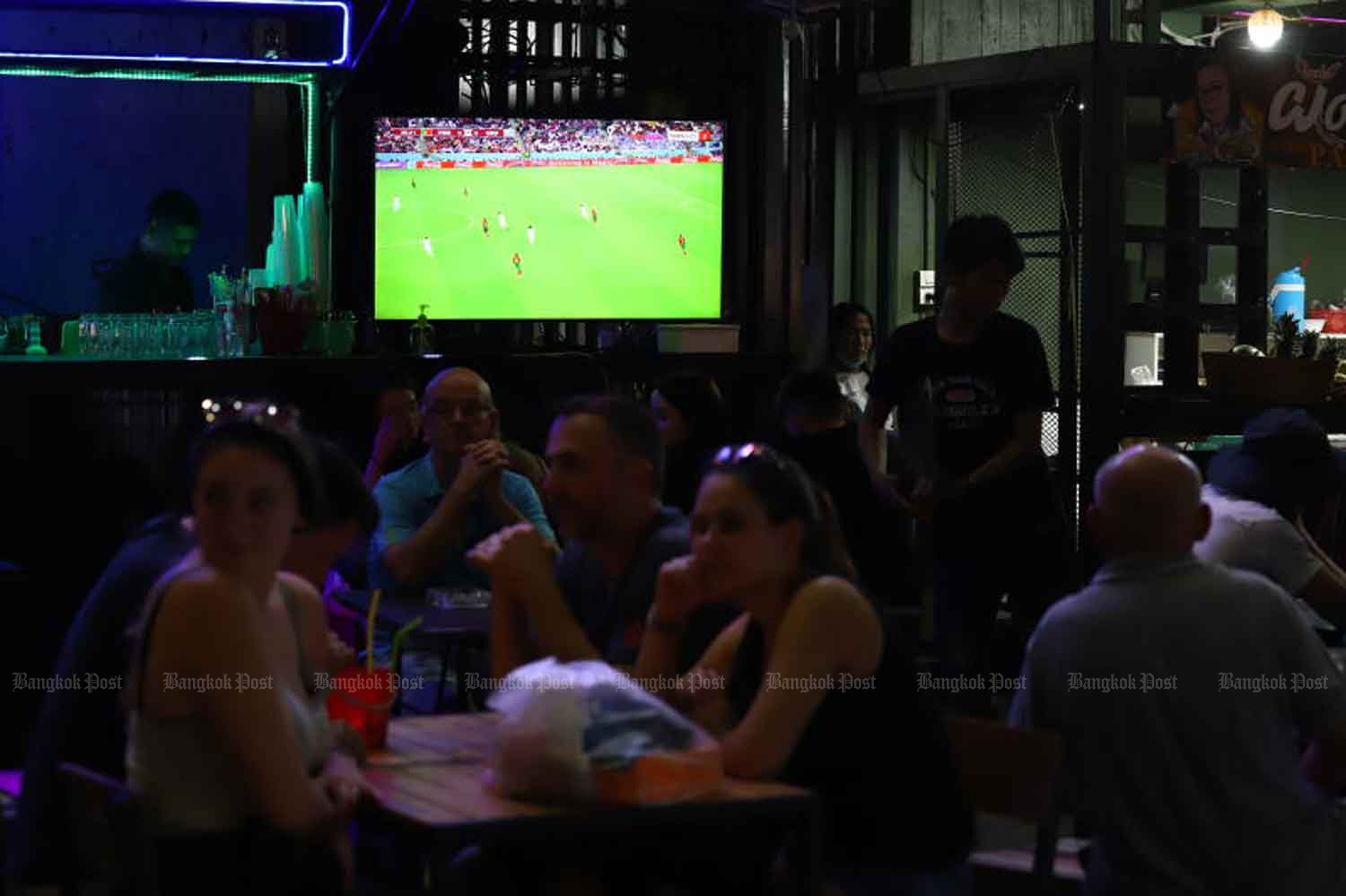 Patrons enjoy a beverage while watching World Cup football at a Bangkok bar. (Photo: Nutthawat Wicheanbut)