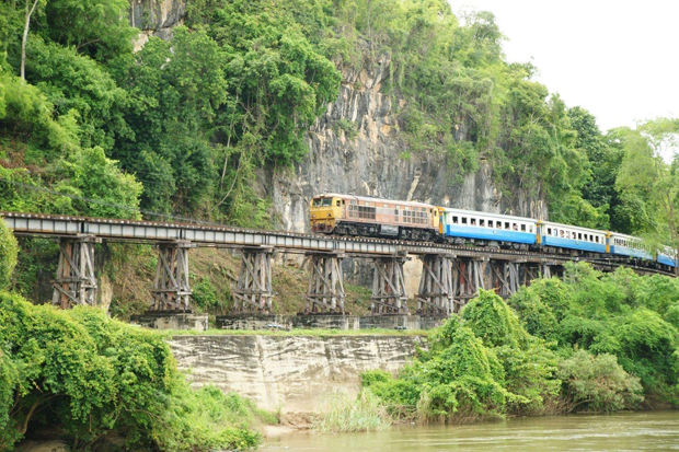 A train passes a famous wooden bridge on the Death Railway in Kanchanaburi province. (Photo: Piyarat Chongcharoen)