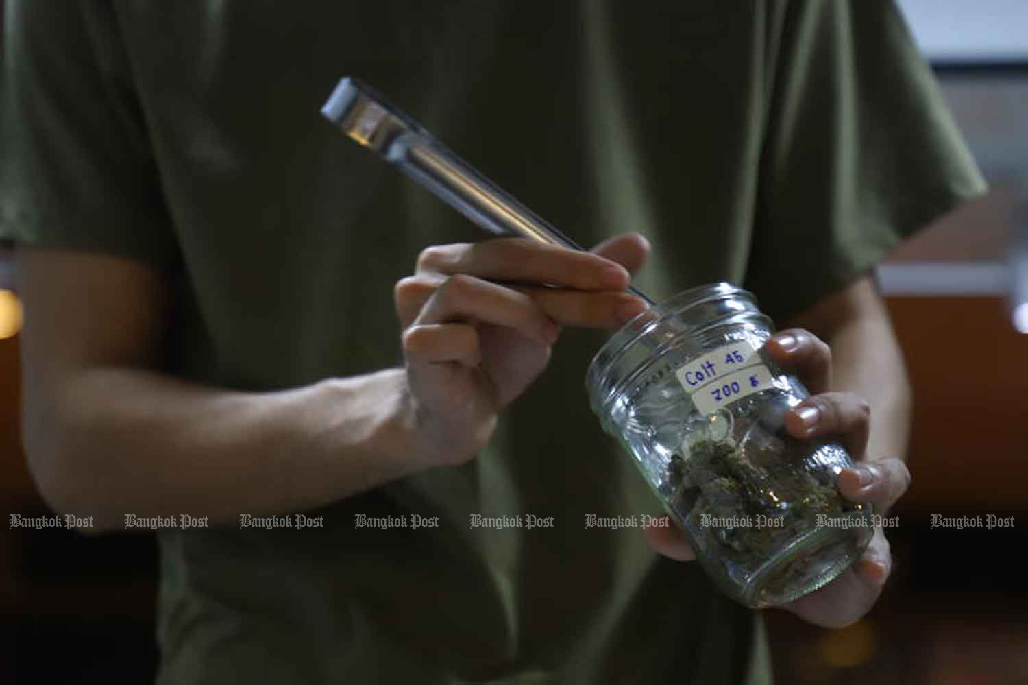 A vendor picks cannabis buds from a jar on Khao San Road in Bangkok in July last year. (Photo: Nutthawat Wicheanbut)