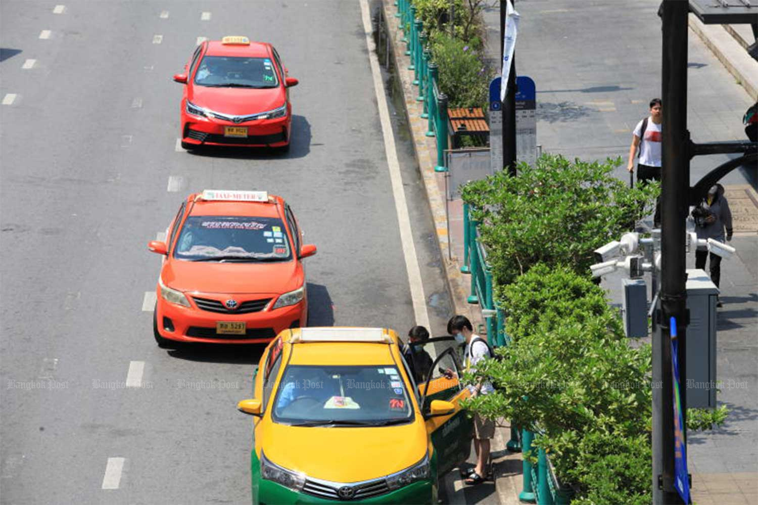 A passenger hails a taxi in front of a shopping complex on Ratchadamri Road in Bangkok. (File photo: Apichart Jinakul)