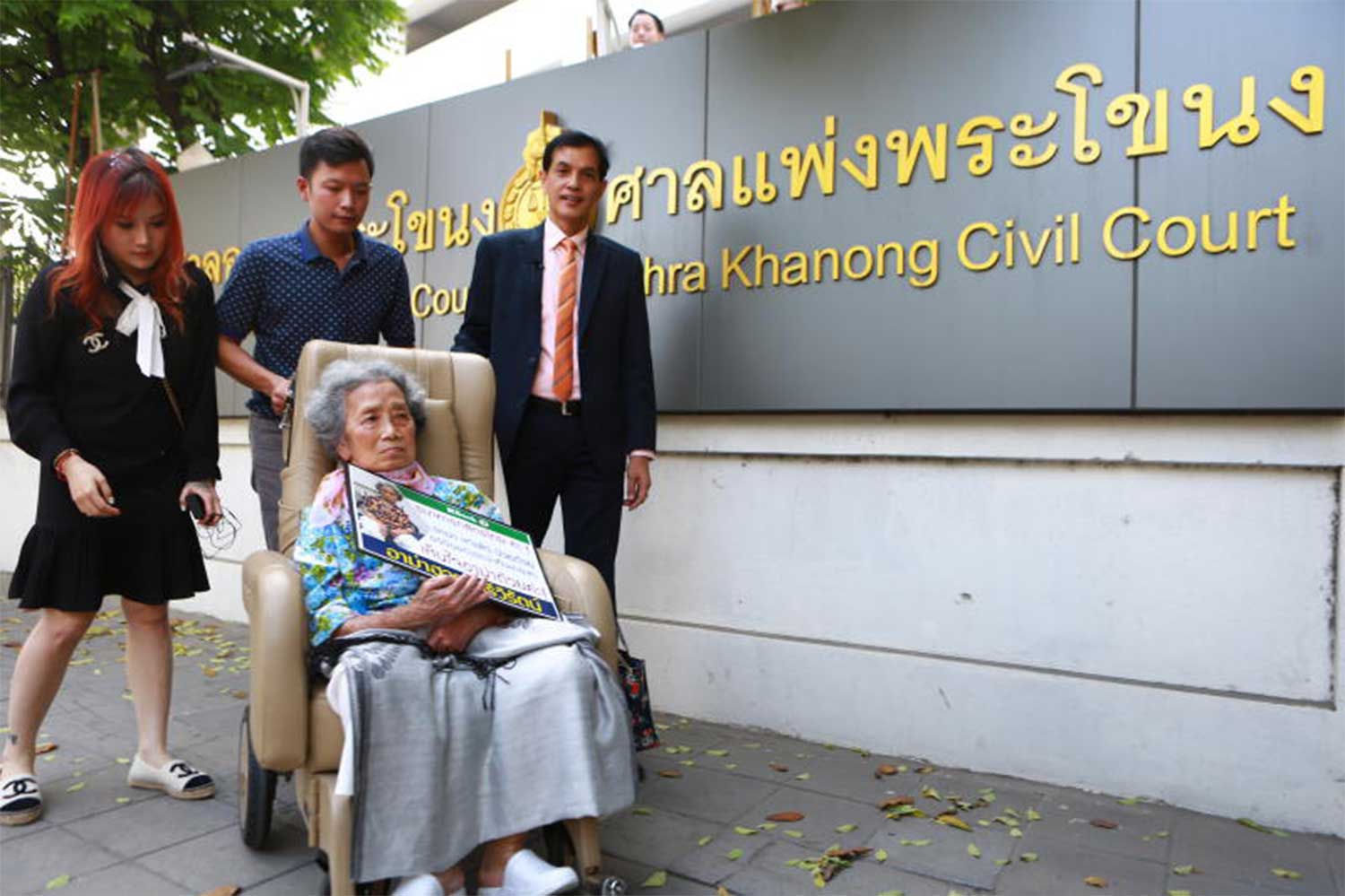 Huay Sriwirat, then 76, arrives at the Phra Khanong Civil Court in Bangkok on November 19, 2021, with her granddaughter Mintra Sriwirat, left, and lawyer Anantachai Chaiyadet, right. (Photo by Somchai Poomlard)