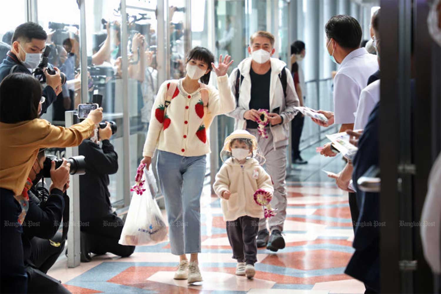 A passenger waves to officials waiting to welcome the first group of Chinese tourists arriving in Thailand at Suvarnabhumi airport on Jan 9. (Photo: Varuth Hirunyatheb)