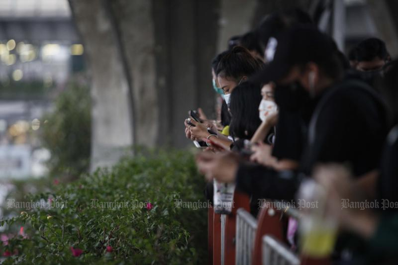 Pedestrians check their smartphones on a bridge in Bangkok. (File photo: Pattarapong Chatpattarasill)