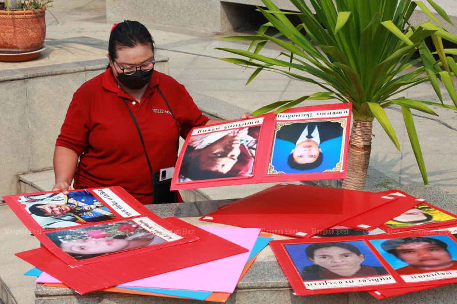 A member of the United Front for Democracy against Dictatorship looks at the portraits of people killed on April 10, 2010, during an event on April 10, 2022 marking the 12th anniversary of the military crackdown on red shirt protesters. (Photo: Apichart Jinakul)