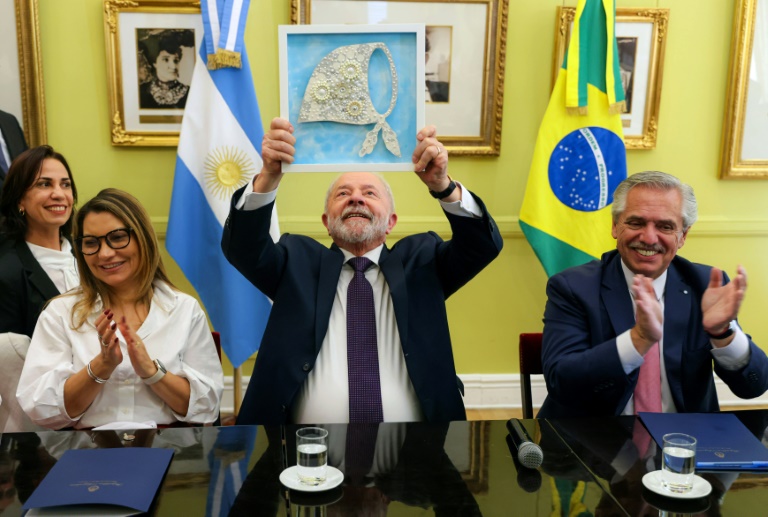 Brazilian President Lula da Silva holds up a symbol of a human rights organisation as his wife and Argentine President Alberto Fernandez applaud at a pre-summit meeting in Buenos Aires on Monday. (Photo: AFP)