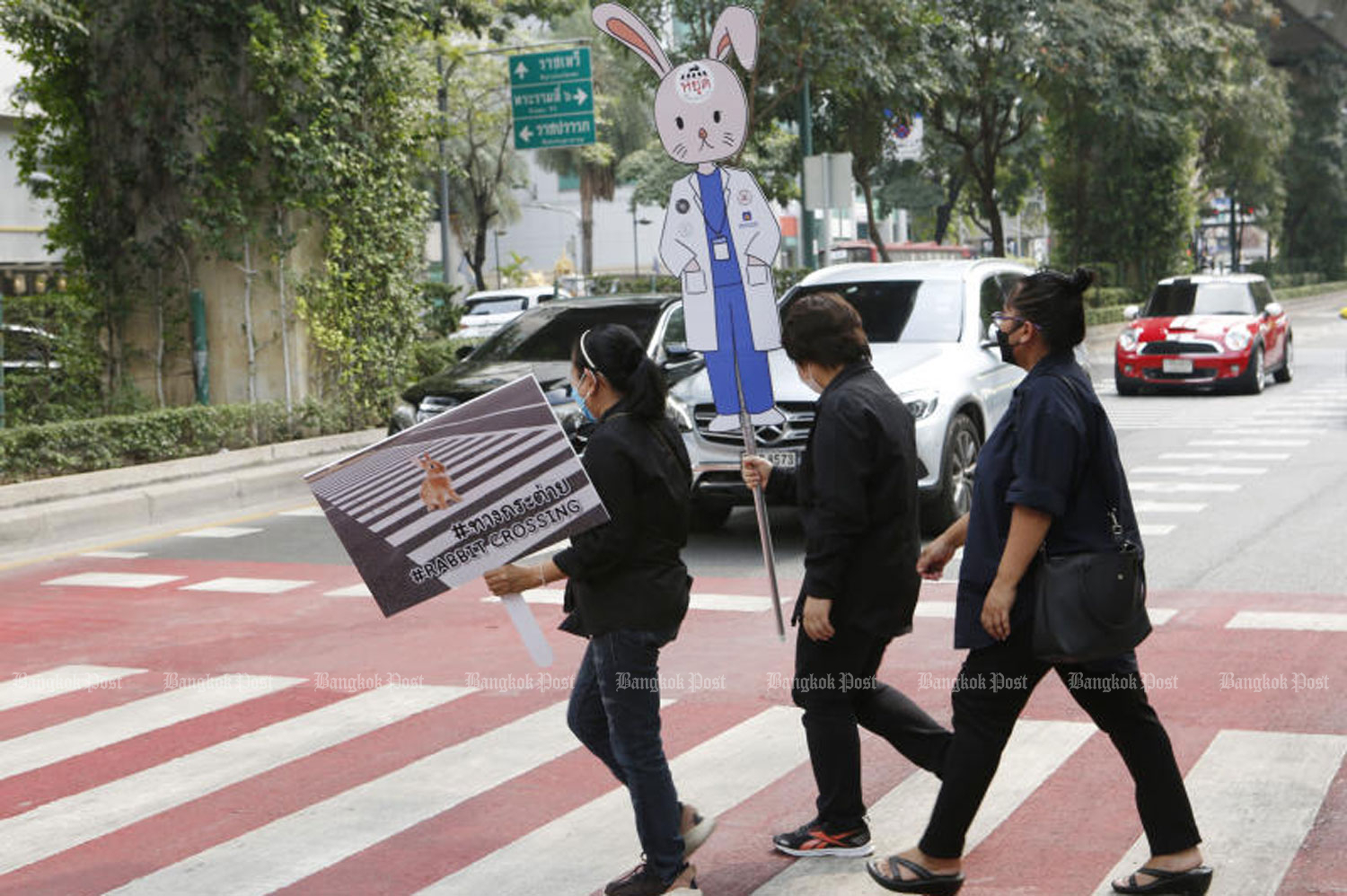 A woman holds up a rabbit sign urging motorists to stop at the pedestrian crossing on Phaya Thai Road in Ratchathewi district, Bangkok, where Dr Waraluck 