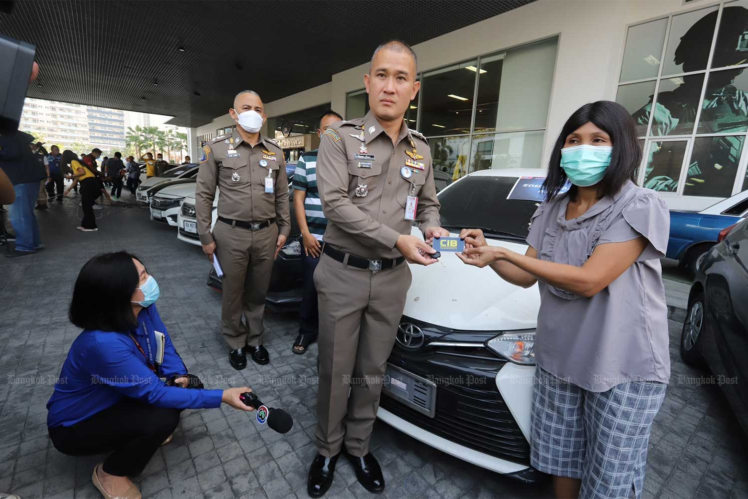 Central Investigation Bureau (CIB) commissioner Pol Lt Gen Jirabhop Bhuridej hands over a car key to a woman who is among hundreds of victims of a major car theft gang. (Photo supplied/Wassayos Ngamkham)