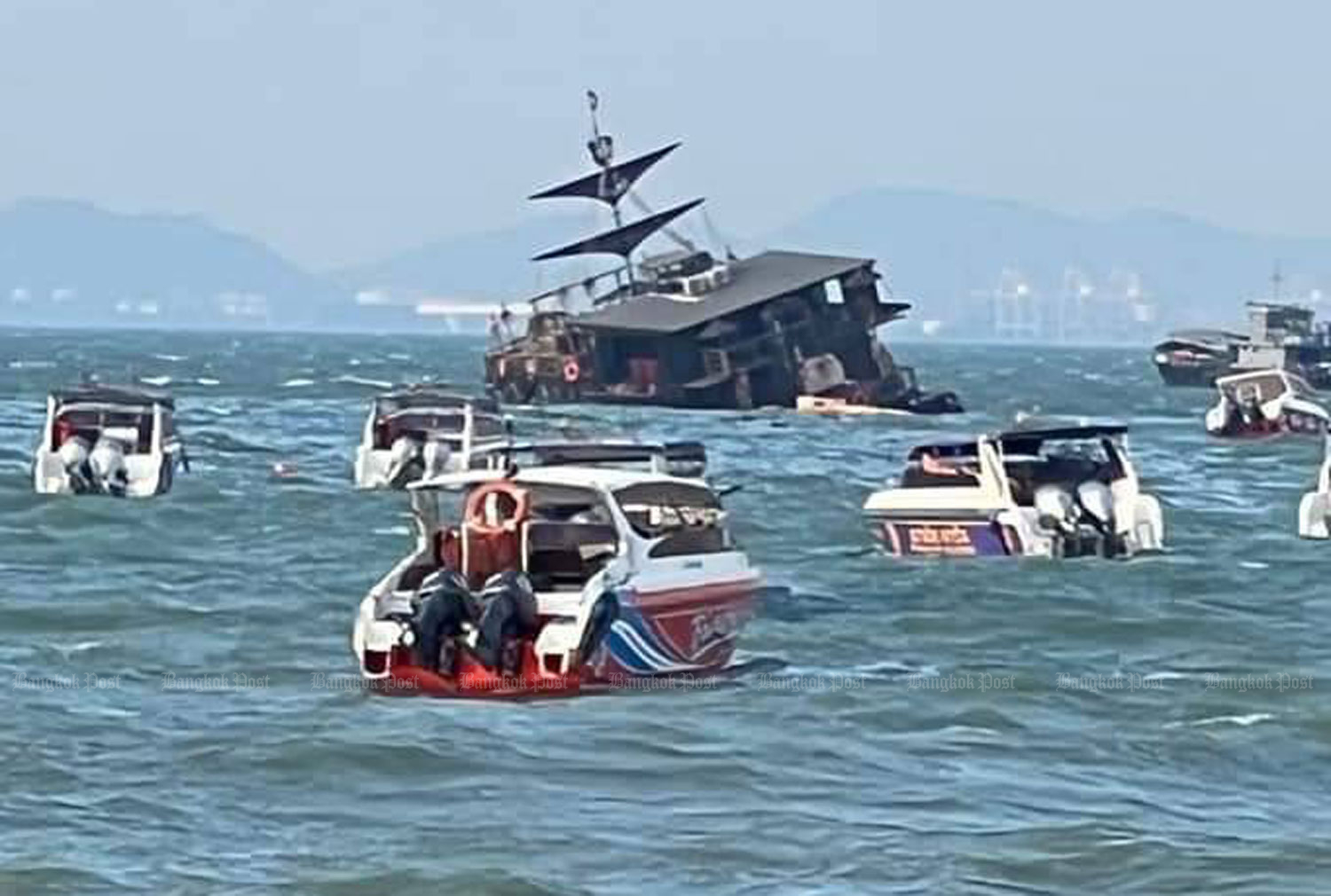 Speedboats standby to help employees aboard the Krakenian floating cafe and restaurant after it was flooded by rough seas off Pattaya, Chon Buri, on Monday evening. Nobody was injured. There were no customers on board. (Photo: Chaiyot Pupattanapong)