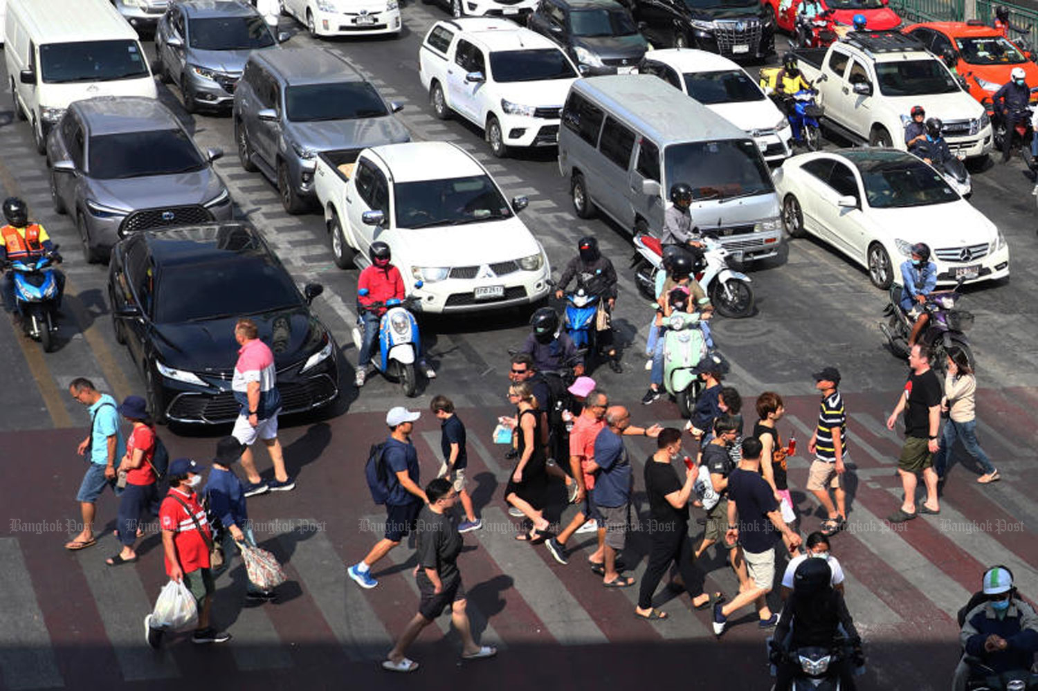 Pedestrians use a crossing at busy Asok intersection in Bangkok. The fine for not stopping has been increased four-fold to 4,000 baht, with loss of one point on the driver's licence. (Photo: Nutthawat Wicheanbut)