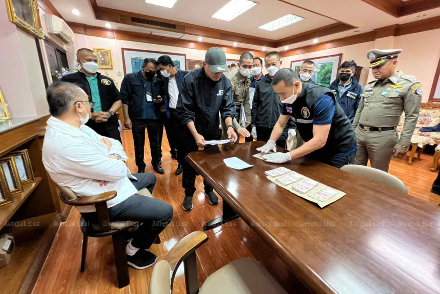 Police examine cash on the desk of the director of Bangchan School in Klong Sam Wa district of Bangkok on Wednesday. (Photo supplied)