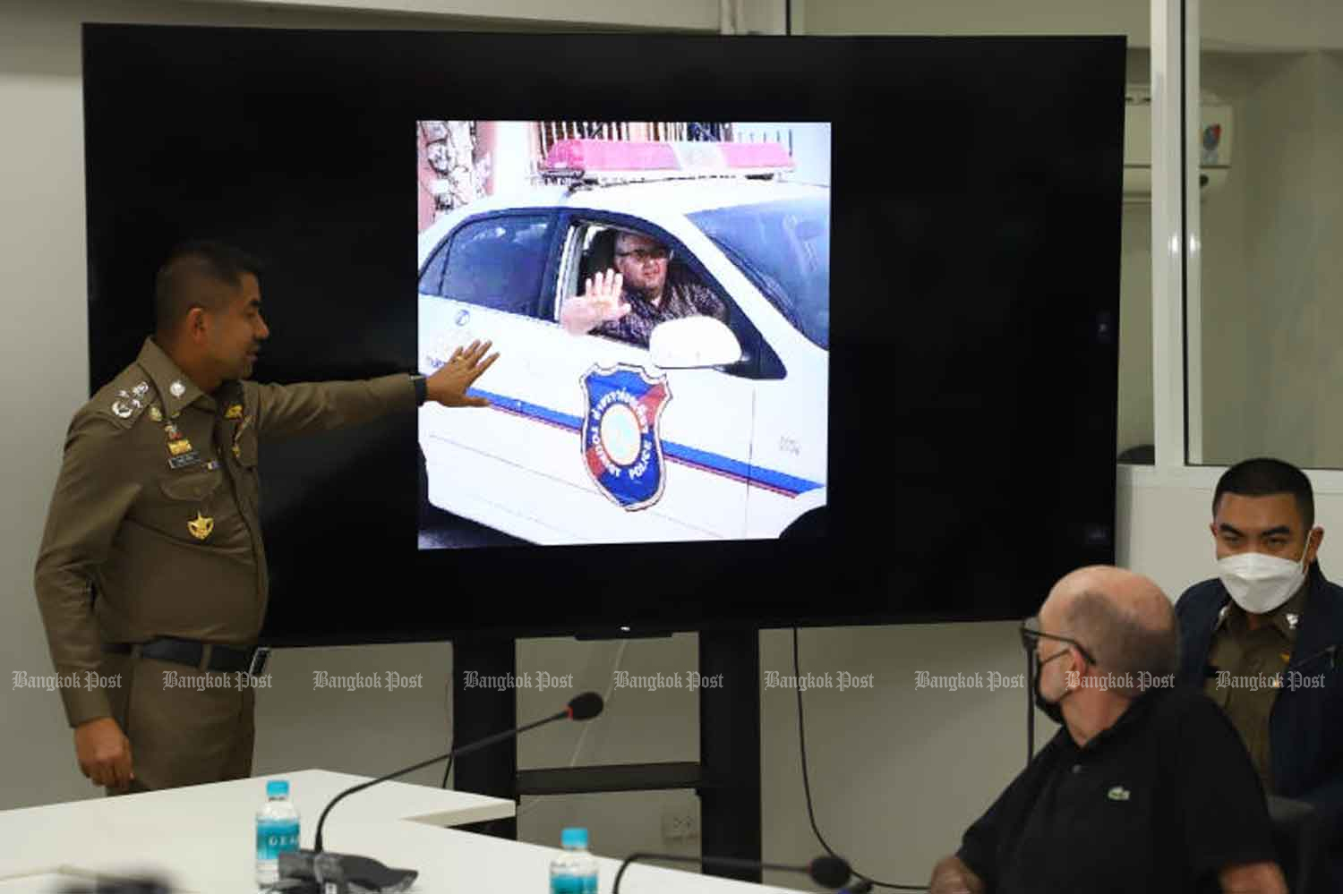 Pol Gen Surachate Hakparn, left, shows a photo of Herve Leonard, 58, posing for pictures in a police car, during a briefing on the arrest of the Frenchman for alleged extortion, fraud and coercion, at the Police Club in Bangkok on Thursday. (Photo: Nutthawat Wicheanbut)