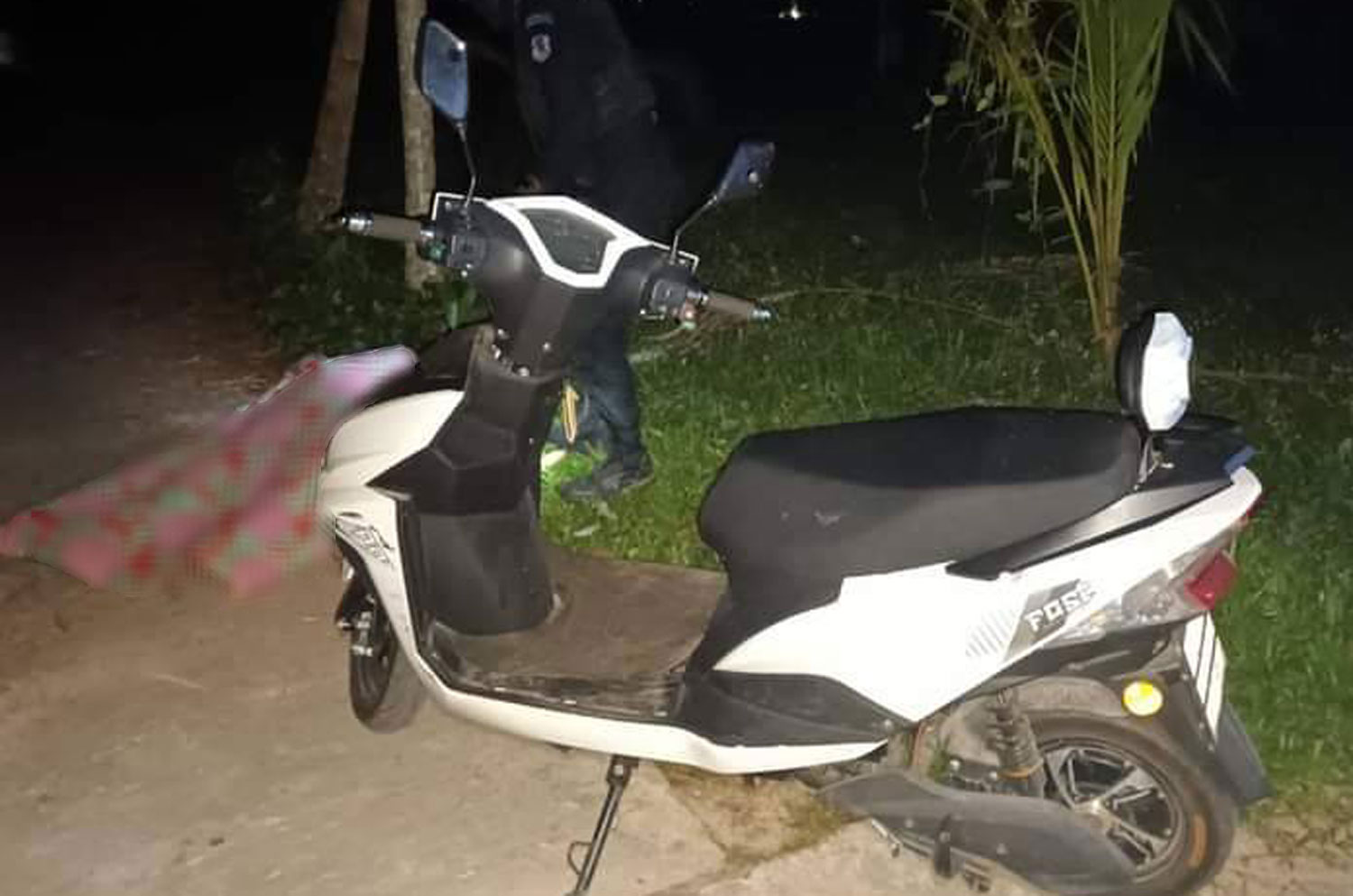 The body of the slain former imam lies covered with a sheet in front of his motorcycle in Pattani's Sai Buri district on Tuesday night. (Photo: Abdullah Benjakat)