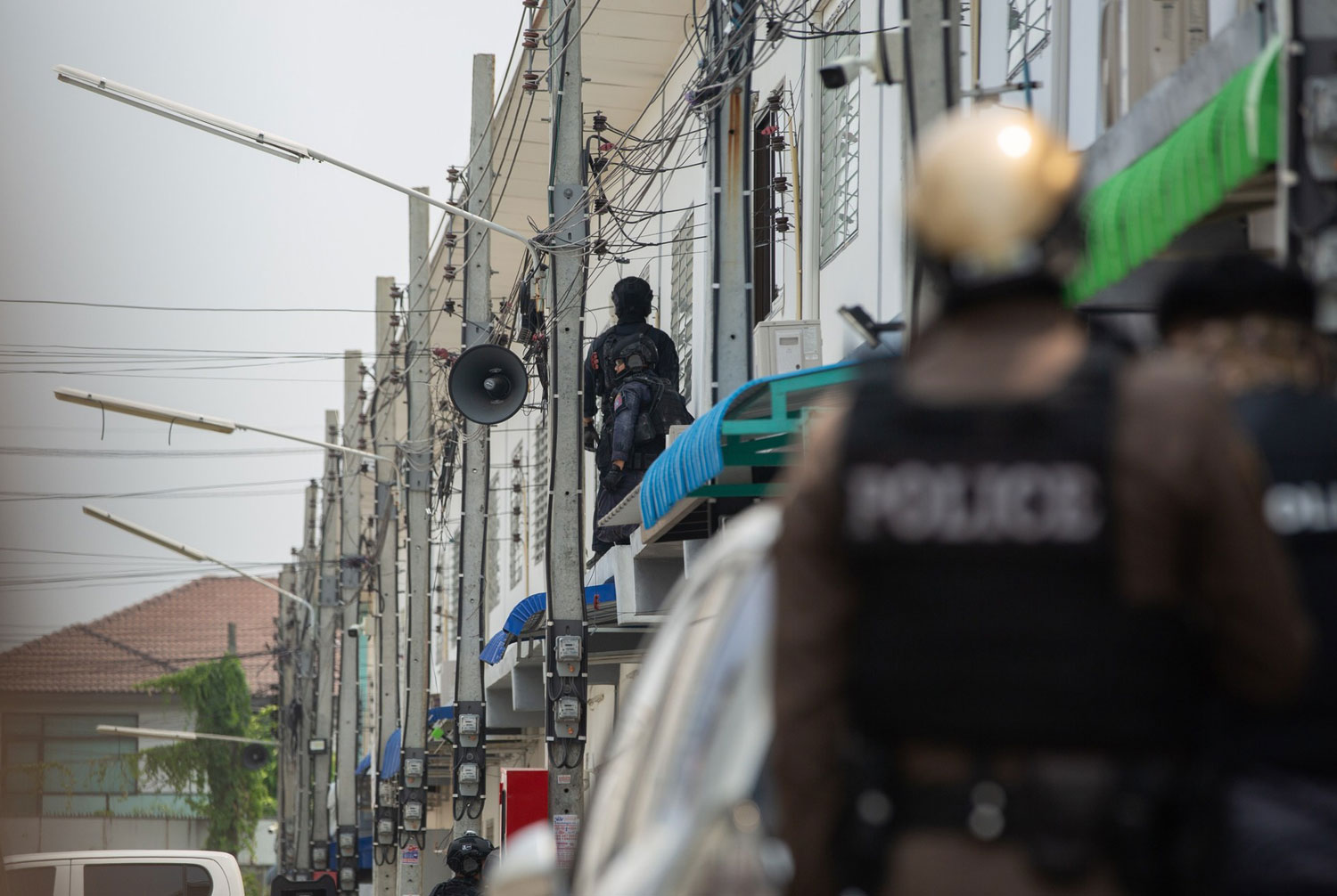 A task force officer climbs to stand near a window of a townhouse in Sai Mai district of Bangkok on Wednesday where a police inspector opened fire from his room. The siege ended shortly after noon on Wednesday. The police-shooter succumbed to his injuries. (Photo: @RoyalthaiPoliceTV Facebook)