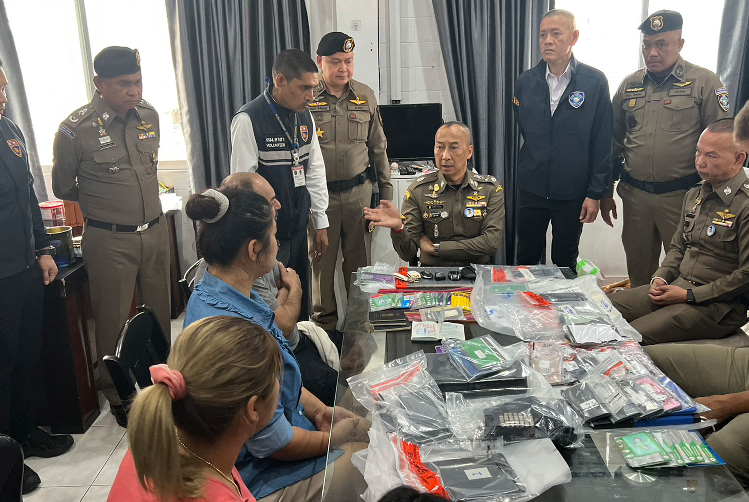 Pol Gen Torsak Sukwimol, deputy national police chief, centre, and senior police question an Indian man and three Thai women detained during raids on Tuesday targeting an international gang of swindlers targeting American retirees. (Photo supplied/ Wassayos Ngamkham)