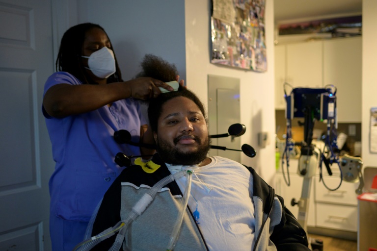 A nurse brushes the hair of gun violence survivor Ralph Norman, who was shot at 17 years old and left quadriplegic, in his apartment in Yonkers, New York