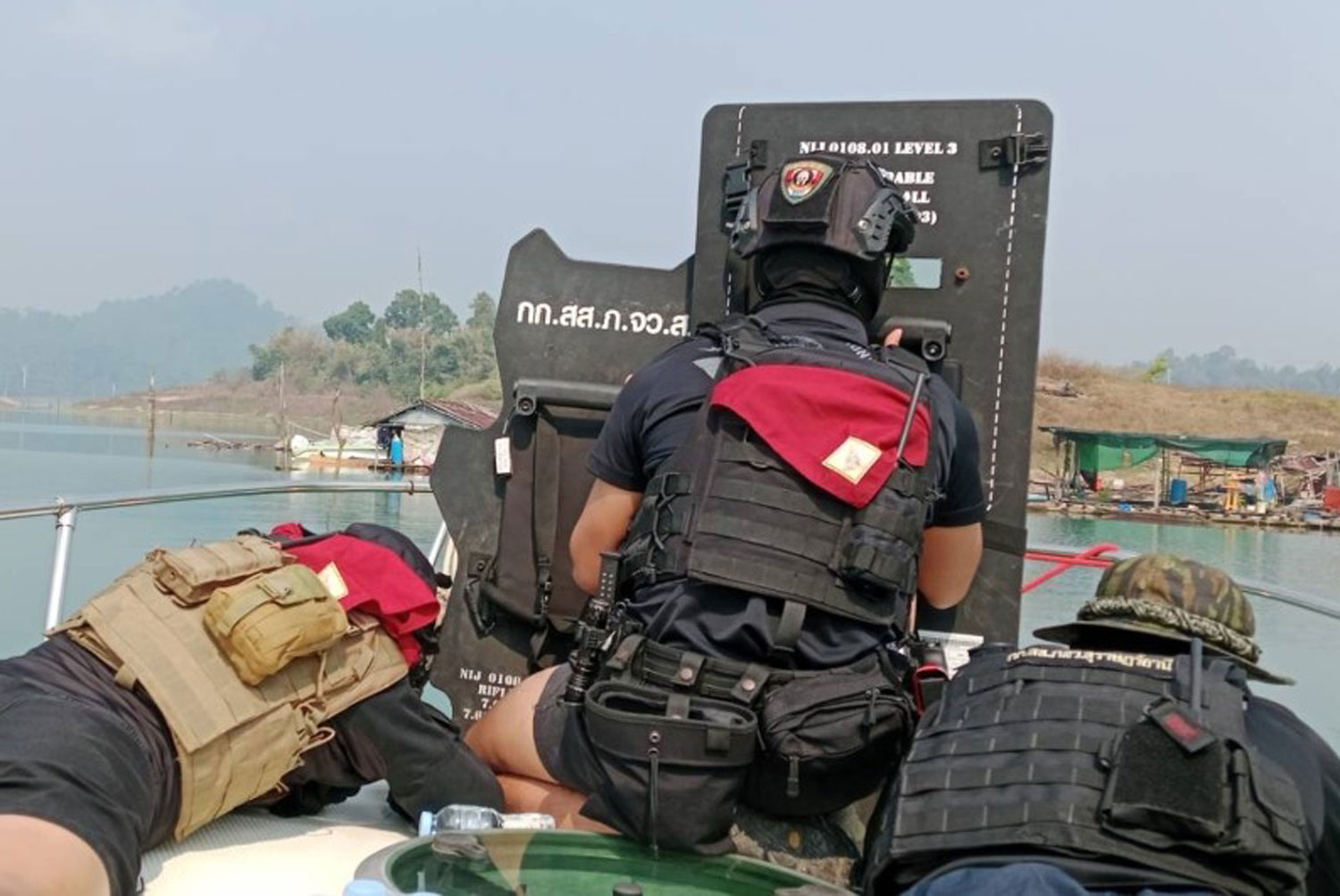 Police wearing protective gear board a boat to search for a police gunman at the Ratchaprapa dam in Surat Thani on Saturday. (Photo: Supapong Chaolan)