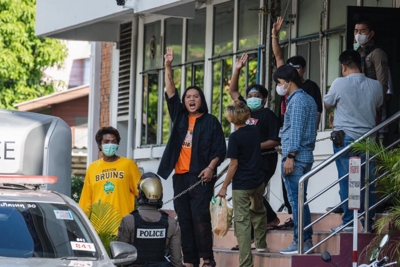 Suspects facing charges after a clash with police on Wednesday give a three-finger salute as they are led from a police station on Friday prior to their court hearing. (Photo: Khai Maew Cheese via Thai Lawyers for Human Rights)