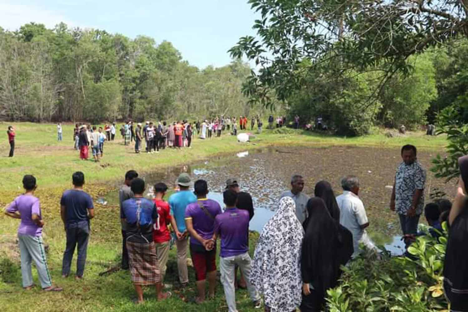 Onlookers gather near the pond where a 3-year-old girl was found dead in tambon Kaluwonuea of Muang district in Narathiwat on Tuesday morning. (Photo: Waedao Harai)