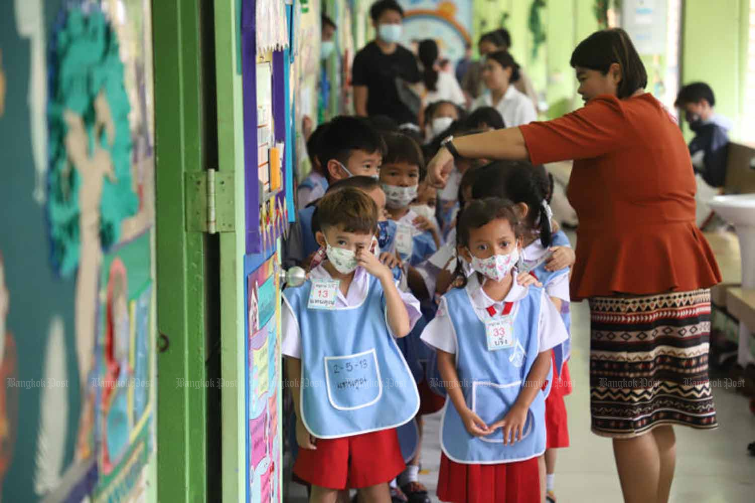 Young children return to classes at Ban Bangkapi School in Bang Kapi district of Bangkok on Tuesday. Health authorities are calling on schools to step up their precautions against Covid-19 as the net term begins. (Photo: Varuth Hirunyatheb)