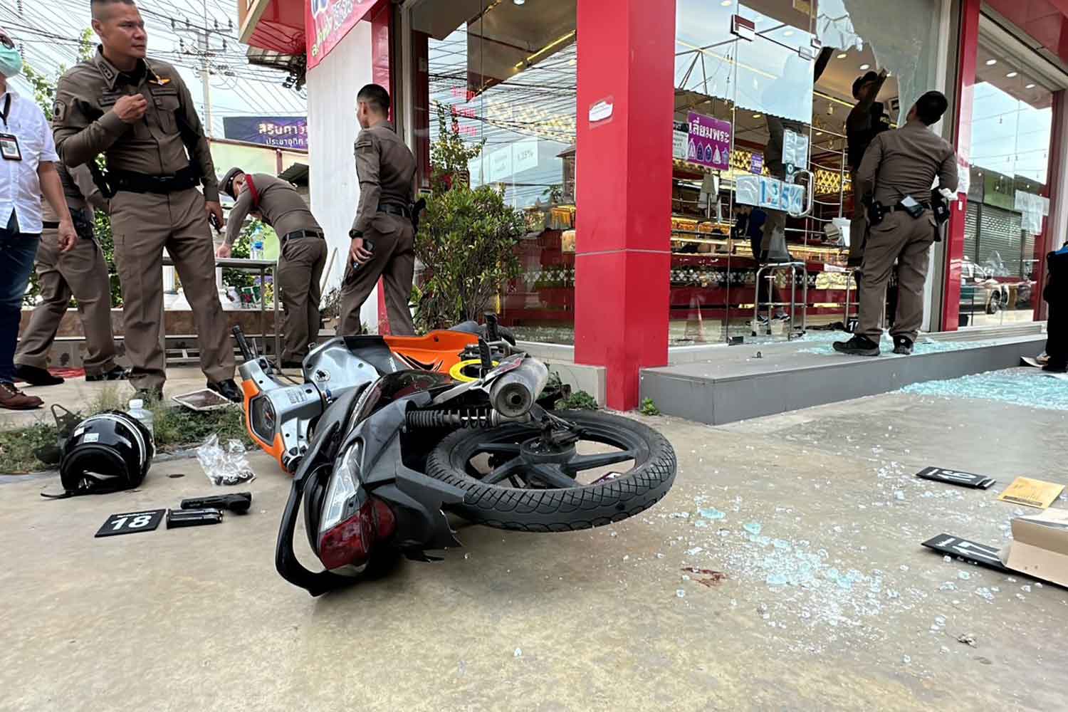 Police examine the scene of gold robbery in Phra Samut Chedi district of Samut Prakan on Wednesday. The motorcycle belonged to the injured robber. (Photo: Sutthiwit Chayutworakan)