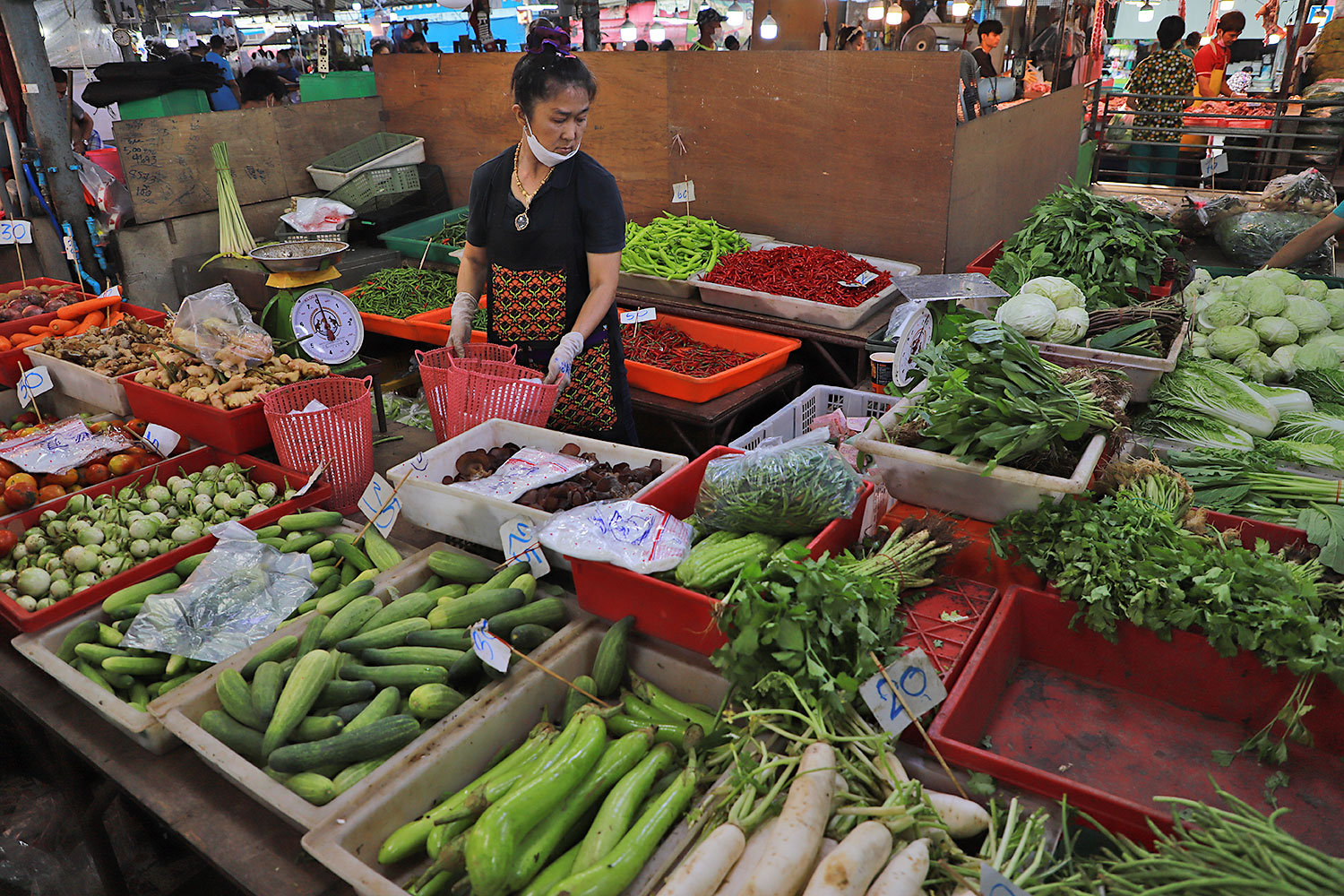 A vendor arranges fresh vegetables at a market. Mr Wattanasak says fresh food prices are relatively stable.