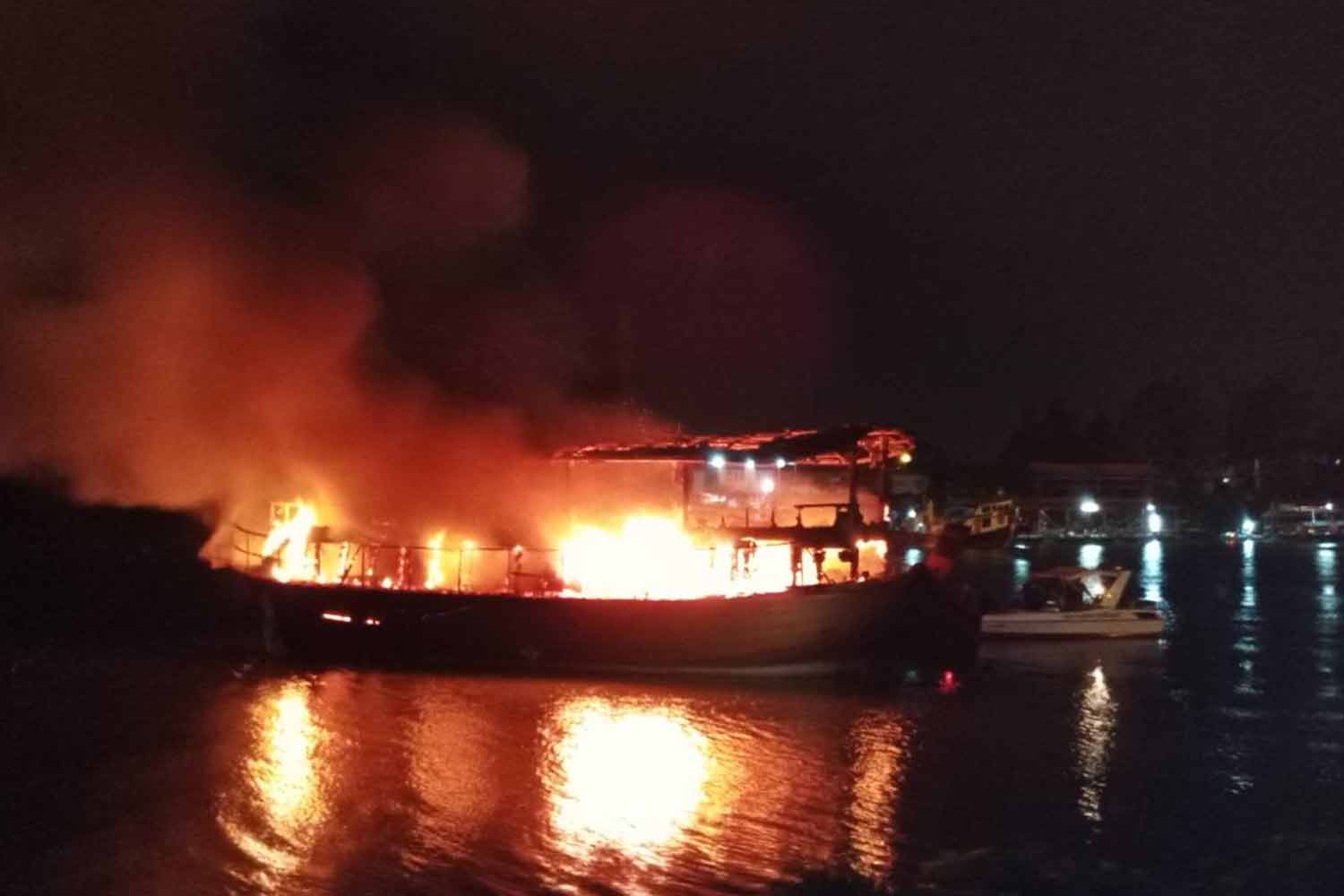 A tour boat, which was modified from a wooden cargo barge, caught fire while being moored at a Chao Phraya river pier in Muang district, Ayutthaya province, early Sunday. Nobody was hurt. (Photo: Sunthorn Pongpao)