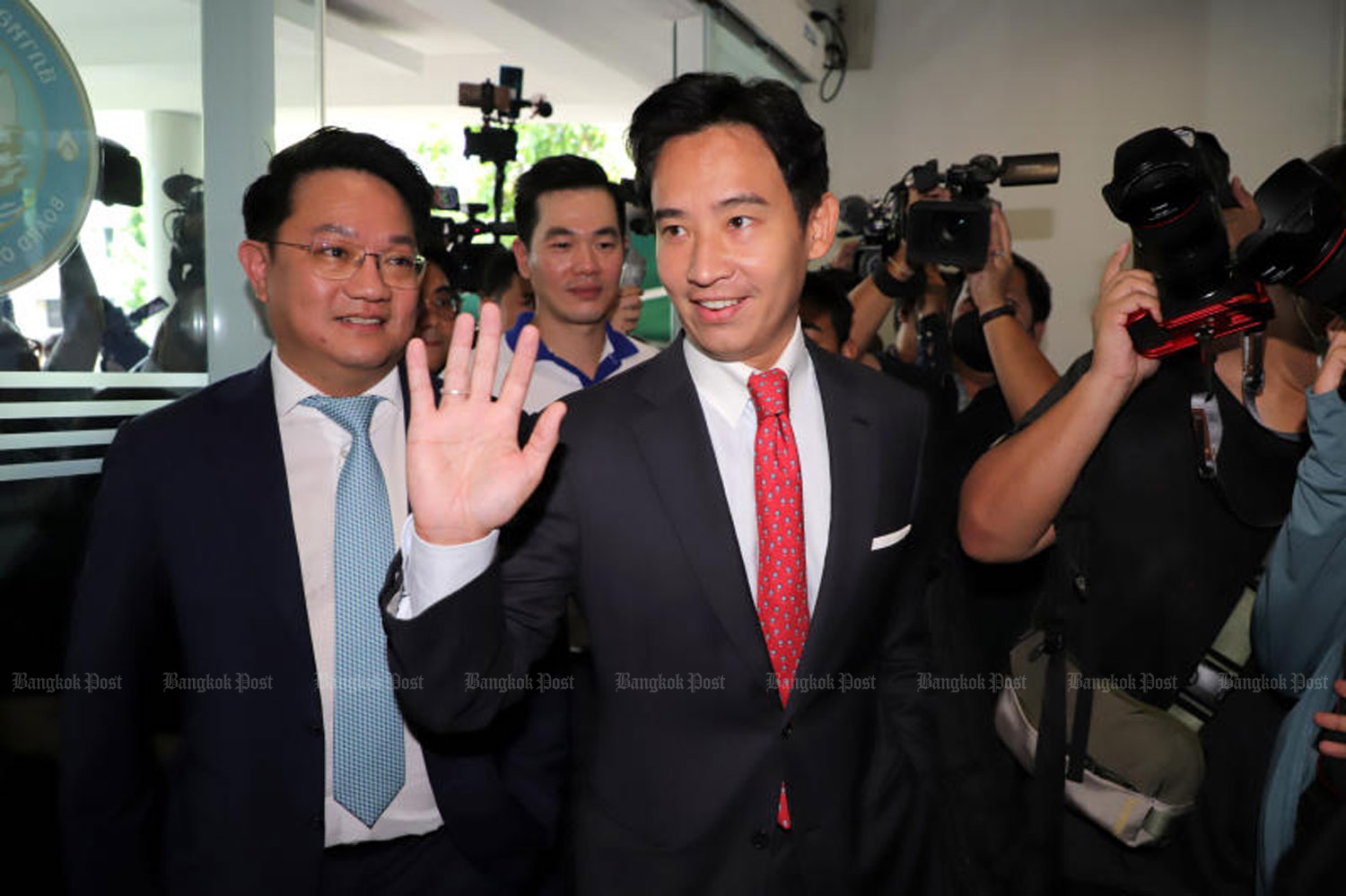 Move Forward leader Pita Limjaroenrat waves to supporters as he arrives at the Thai Chamber of Commerce offices to discuss his economic policies with business leaders on Wednesday. (Photo: Chanat Katanyu)