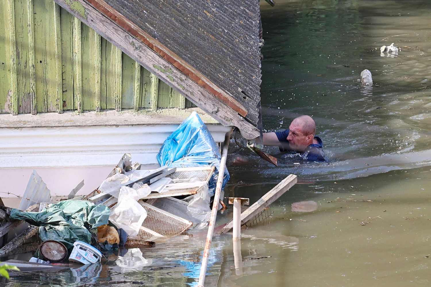 A local resident swims by a house in a flooded area of Kherson on Wednesday, following the destruction of the Kakhovka dam near the city in southern Ukraine. (Photo: AFP)