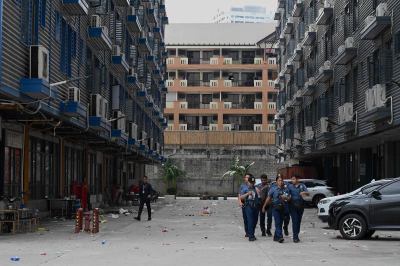 Police officers walk through a compound where they raided several buildings being used by online gaming and scam operations, in Metro Manila on Tuesday. (Photo: AFP)