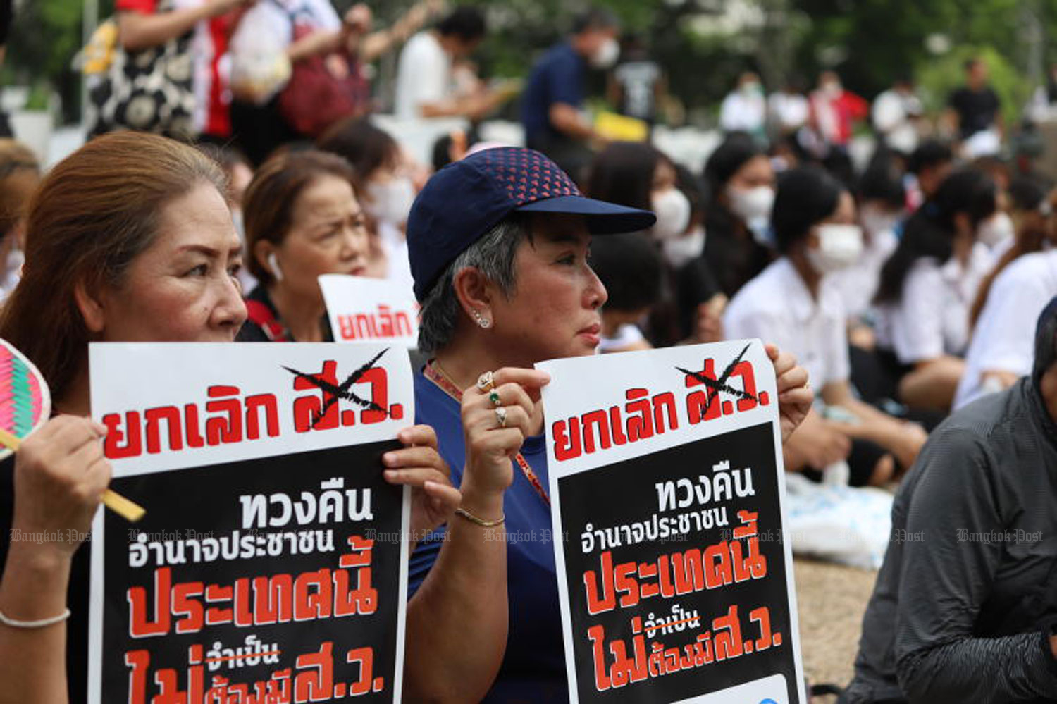 Axe those senators: Two demonstrators on Friday hold placards reading 'This country does not want senators' during a gathering of demonstrators in front of Kasetsart University's auditorium in Bang Khen district, Bangkok. They converged there to protest against senators who did not vote for Pita Limjaroenrat as PM. (Photo: Pattarapong Chatpattanasill)