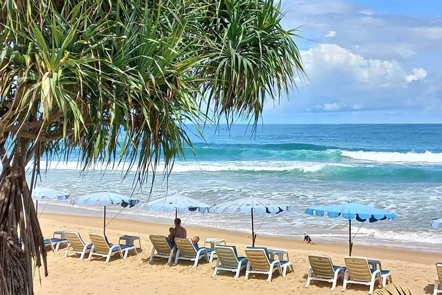 A family of tourists relax on Karon Beach, the longest beach in Phuket. (Photo: Achadthaya Chuenniran)