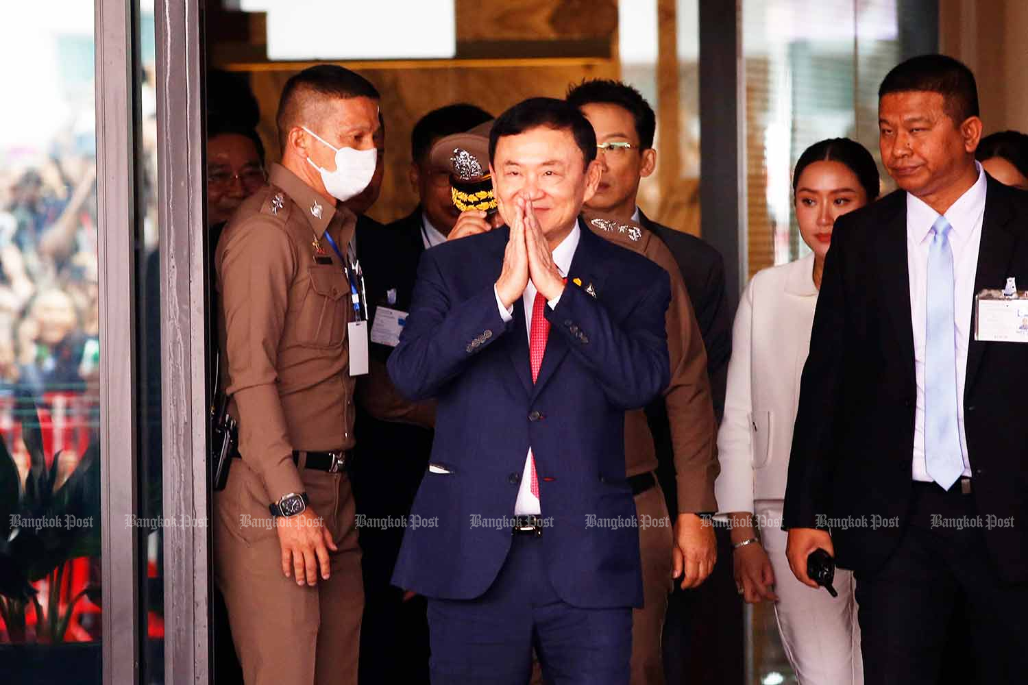 Former prime minister Thaksin Shinawatra smiles and greets supporters with a wai as he emerges from the private jet terminal at Don Mueang airport on Tuesday morning. (Photo: Wichan Charoenkiatpakul)