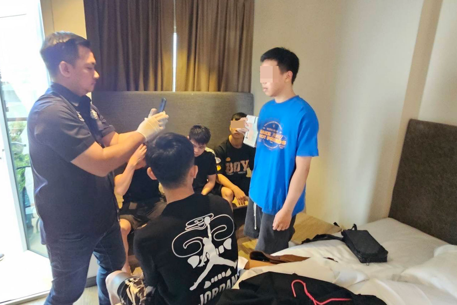 Police arrest 13 Vietnamese men for operating online gambling during the raid on three hotel rooms in Pattaya, Chon Buri, early Tuesday morning. Faces blurred by police. (Photo supplied/ Chaiyot Pupattanapong)