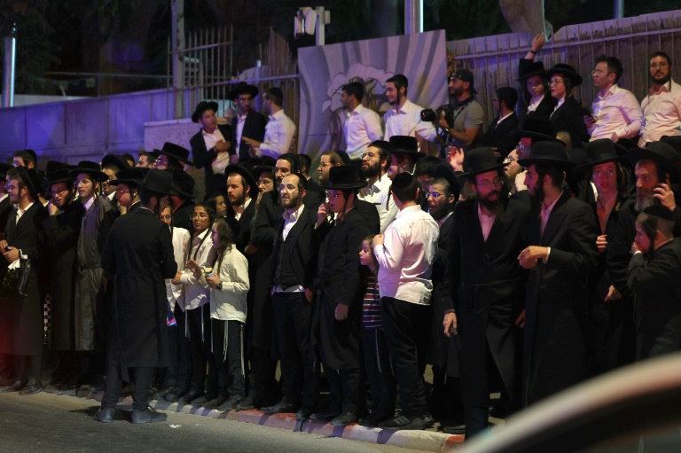 Ultra-Orthodox Jewish bystanders watch emergency and security personnel at the scene of the attack.