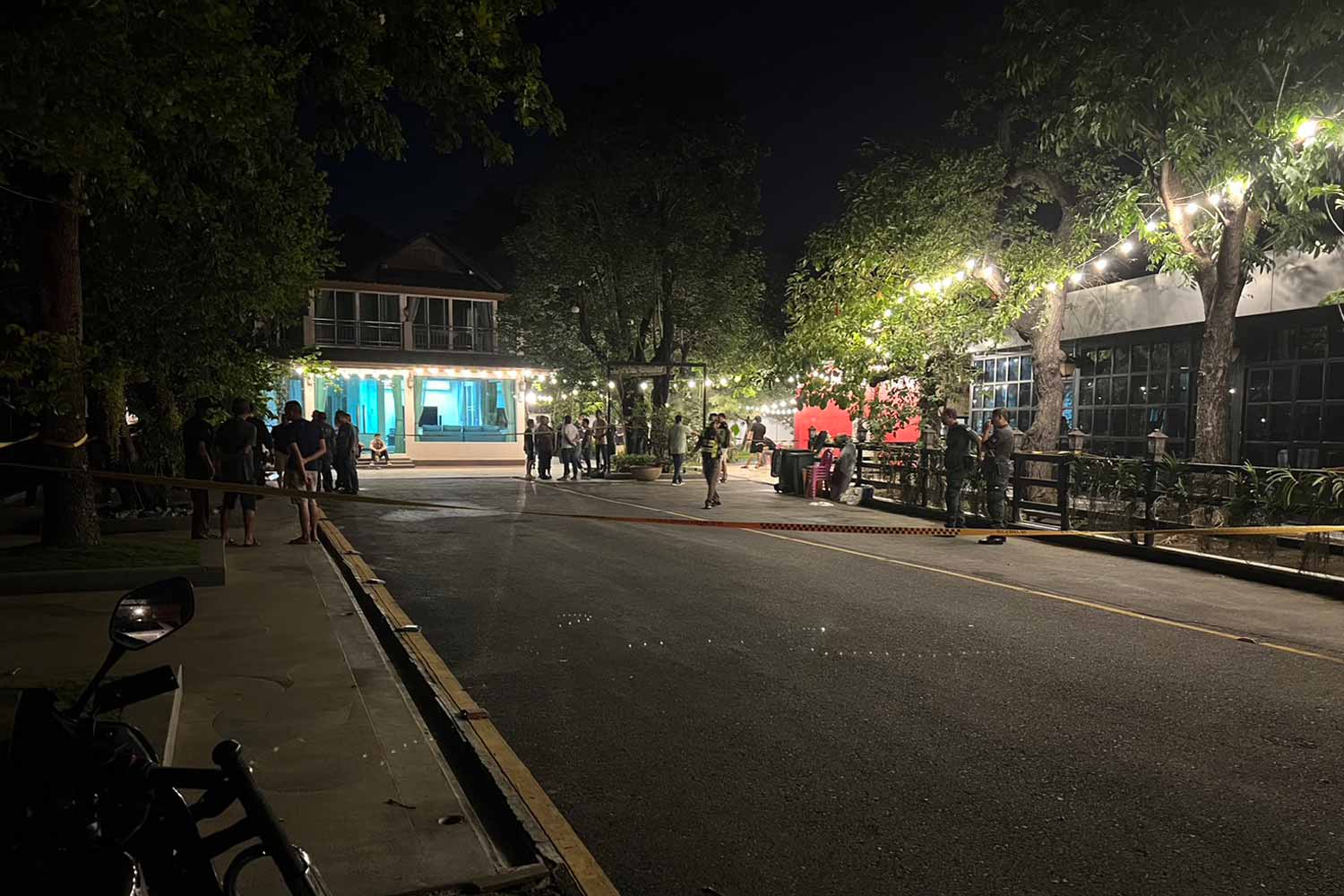 Police and local residents gather near the house in tambon Takong in Muang district of Nakhon Pathom, where a highway police officer was killed and another seriously injured by a gunman on Wednesday night. A warrant has been issued for the arrest of the gunman. (Photo supplied)