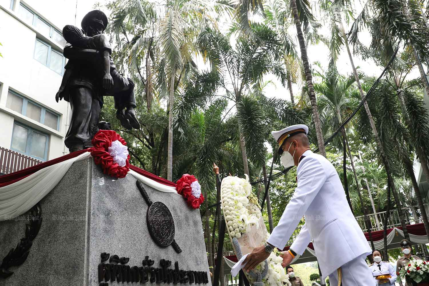 A commissioner lays a wreath in front of a monument featuring the image of a police officer helping a civilian, at the headquarters of the Provincial Police Region 1 in Bangkok. (File photo: Pattarapong Chatpattarasill)