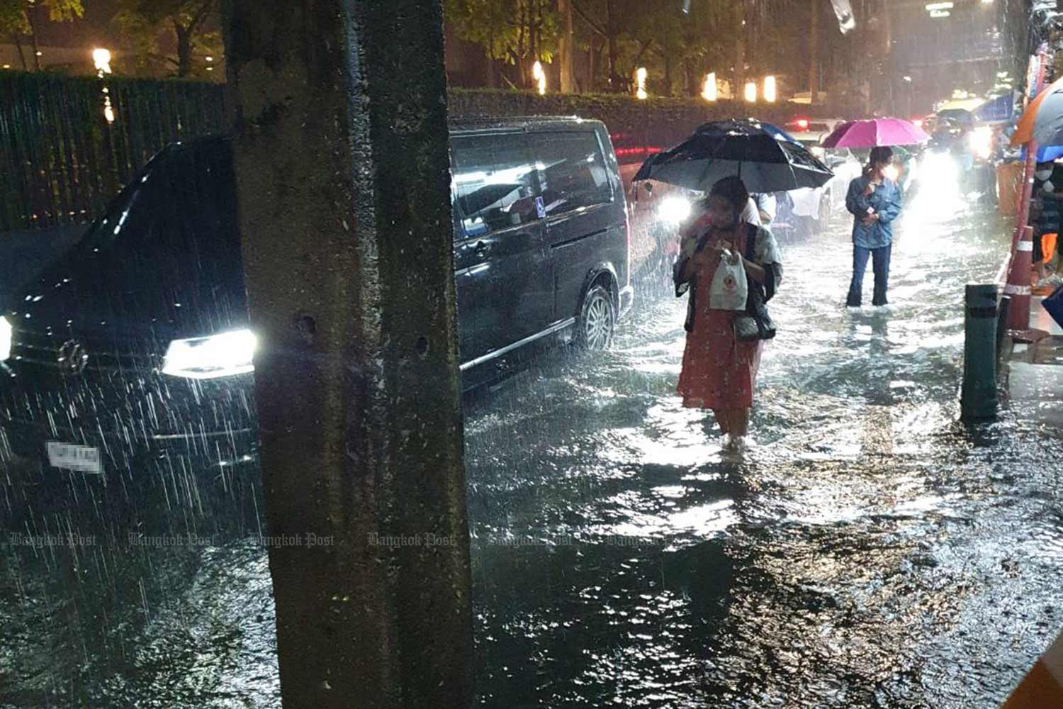 Pedestrians wade through floodwater alongside vehicles as rain buckets down on a section of Sukhumvit Road in Bangkok on Tuesday evening. (Photo supplied)