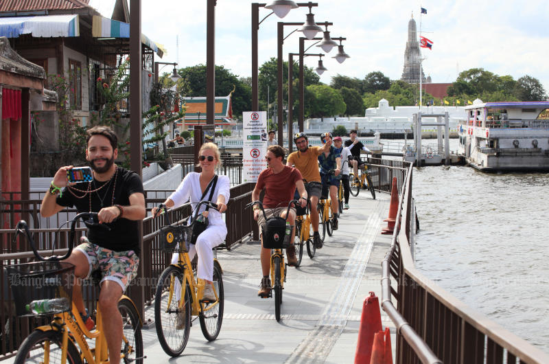 Tourists cycle on a path along the Chao Phraya River, Bangkok. (Photo: Apichart Jinakul)