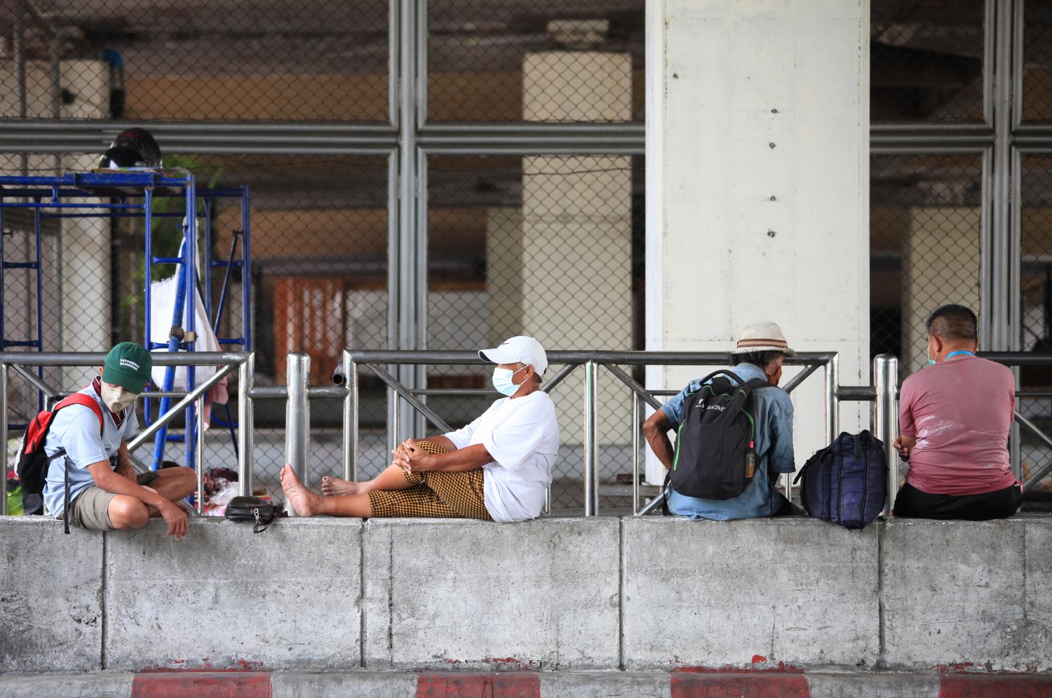 Homeless people relax sitting on a concrete block underneath Phra Pin Klao bridge near Ratchadamnoen Avenue in Bangkok. (Photo: Apichart Jinakul)