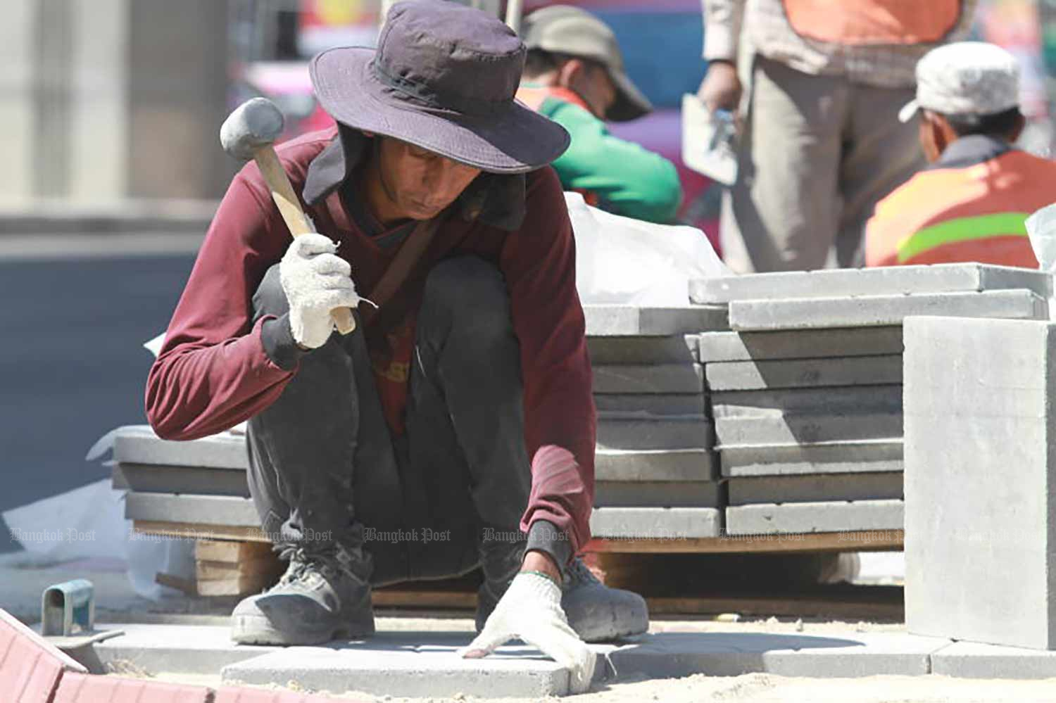 A worker lays paving stones in the midday heat on the eve of May Day in 2019. (Photo: Somchai Poomlard)