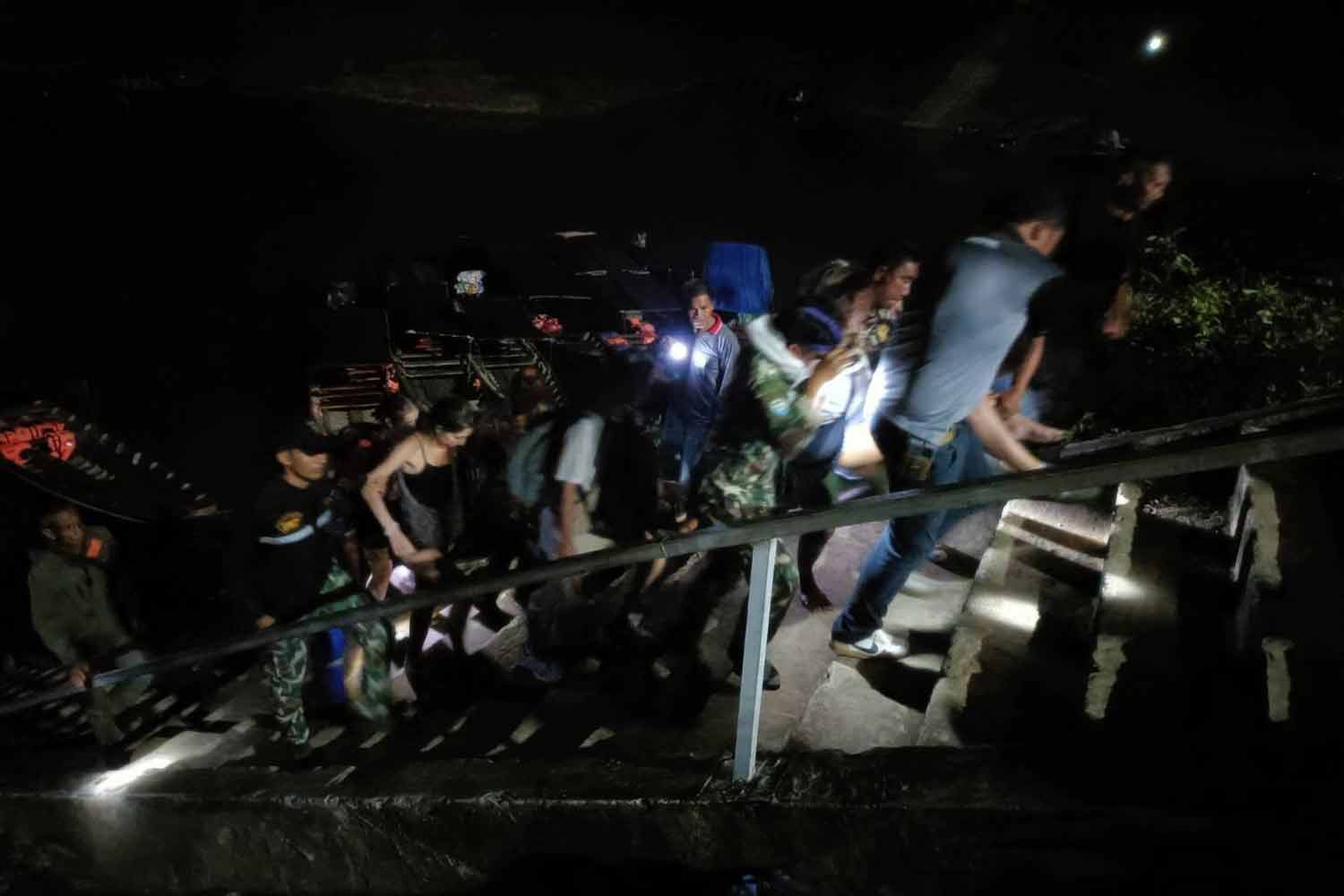 Tourists rescued from flooded Nam Talu cave arrive at the Rajjaprabha Dam reservoir pier in Surat Thani on Tuesday night. (Photo: Supapong Chaolan)