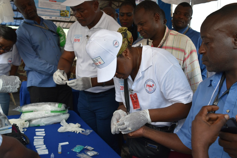 Dr Jeanine Musau, senior malaria technical adviser for the DRC Integrated Health Project, demonstrates the use of malaria rapid diagnostic tests for US Embassy staff in Kinshasa, DR Congo. (Photo: Alain Mukeba, USAID DRC Communication Specialist via Wikimedia Commons)