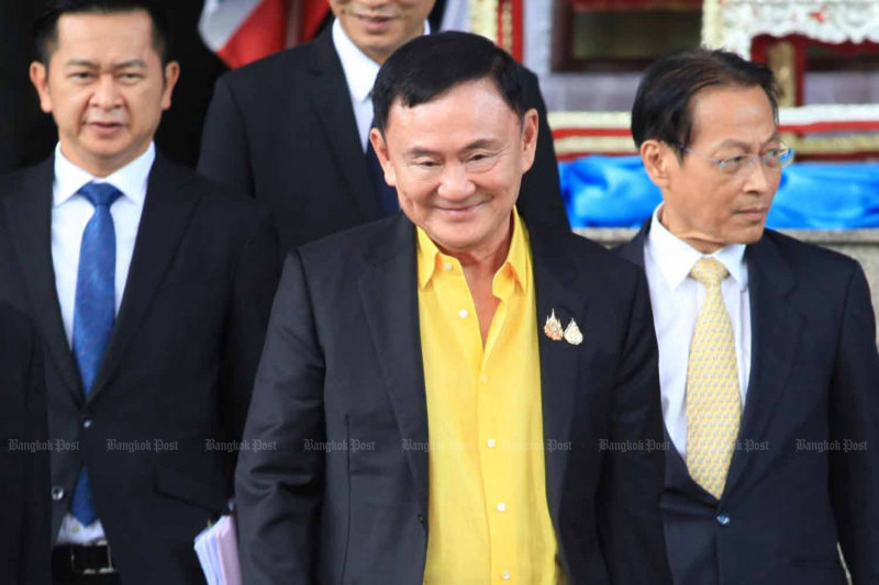 Former premier Thaksin Shinawatra leaves the Criminal Court in Bangkok on August 19 last year after a scheduled hearing of lese majeste charges brought against him. His lawyer Winyat Chatmontree is on the left. (Photo: Apichart Jinakul)