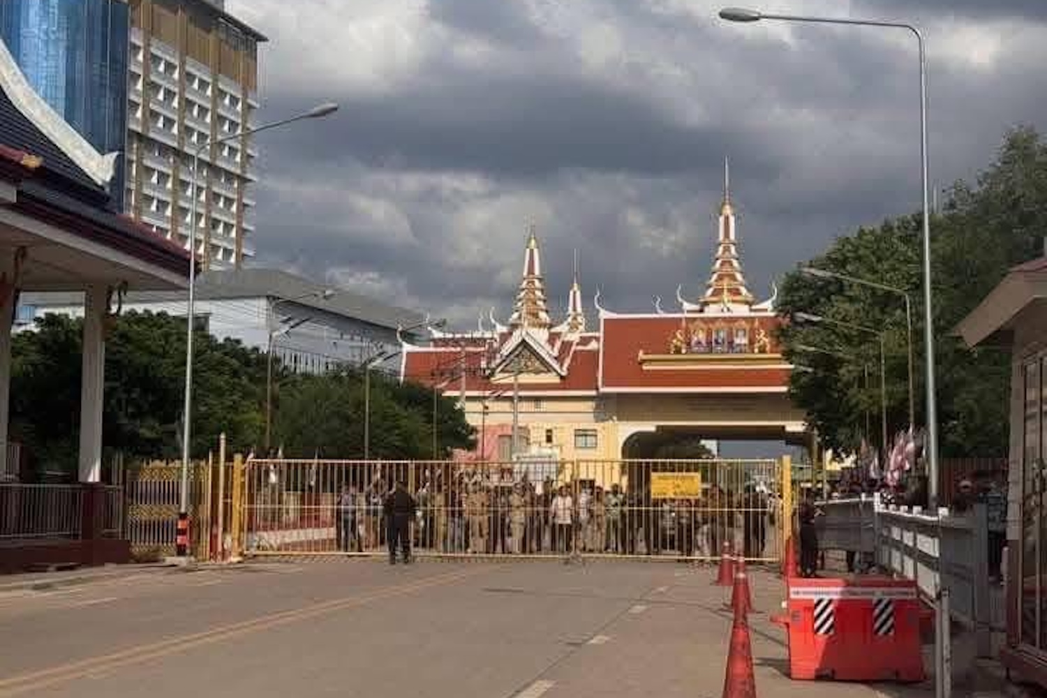People wait behind a barricade at the Ban Khlong Luek border checkpoint in Aranyaprathet district of Sa Kaeo province on Saturday afternoon. (Sa Kaeo radio, Public Relations Department Facebook)