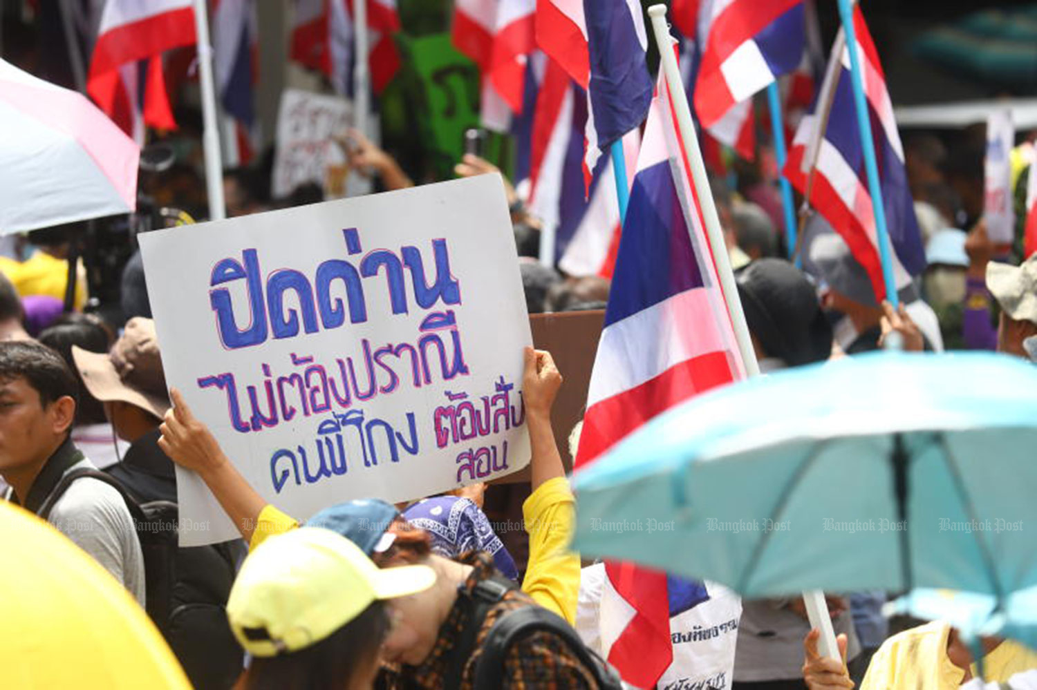 One protester holds a placard with a message “Close border checkpoints. No mercy. Cheats must be taught a lesson’’. (Photo: Nutthawat Wichieanbut)