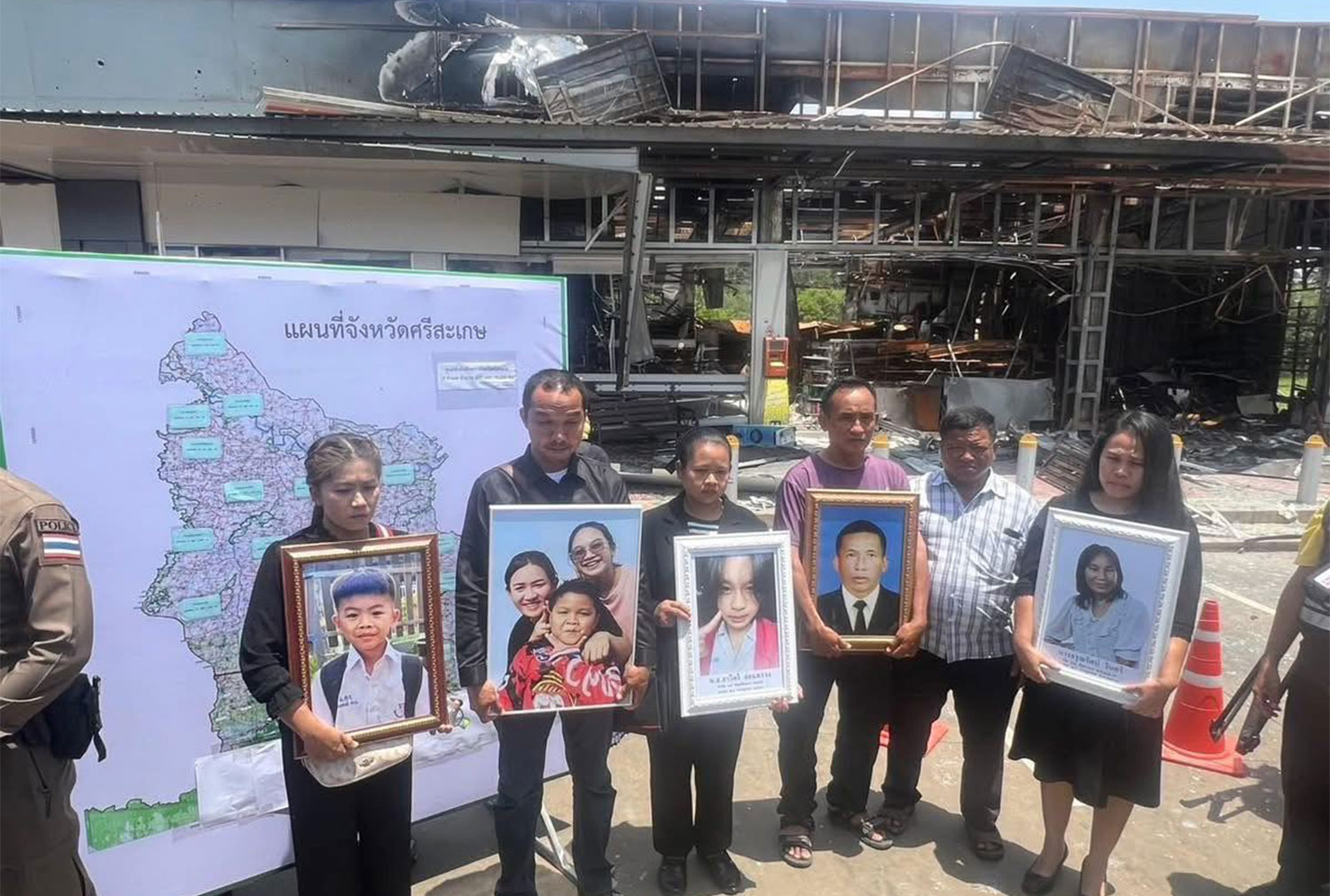 Families of those who were killed when Cambodia's rockets fell into the convenience store at the PTT petrol station in Ban Phue of Si Sa Ket province on July 24 gather in front of the damaged store on Friday, with photos of their loved ones. (Photo: Second Army Region)
