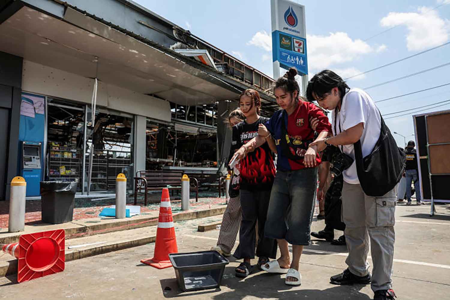 Tungnang Boonterm, 39, injured from an artillery shell that hit a destroyed 7-Eleven convenience store and gas station on July 24, which also resulted in multiple fatalities, is assisted as she walks after an inspection of the site by foreign military attaches from major powers and ASEAN member countries, along with diplomats from 23 countries, following a ceasefire between Cambodia and Thailand, in Sisaket province, Thailand, August 1, 2025。