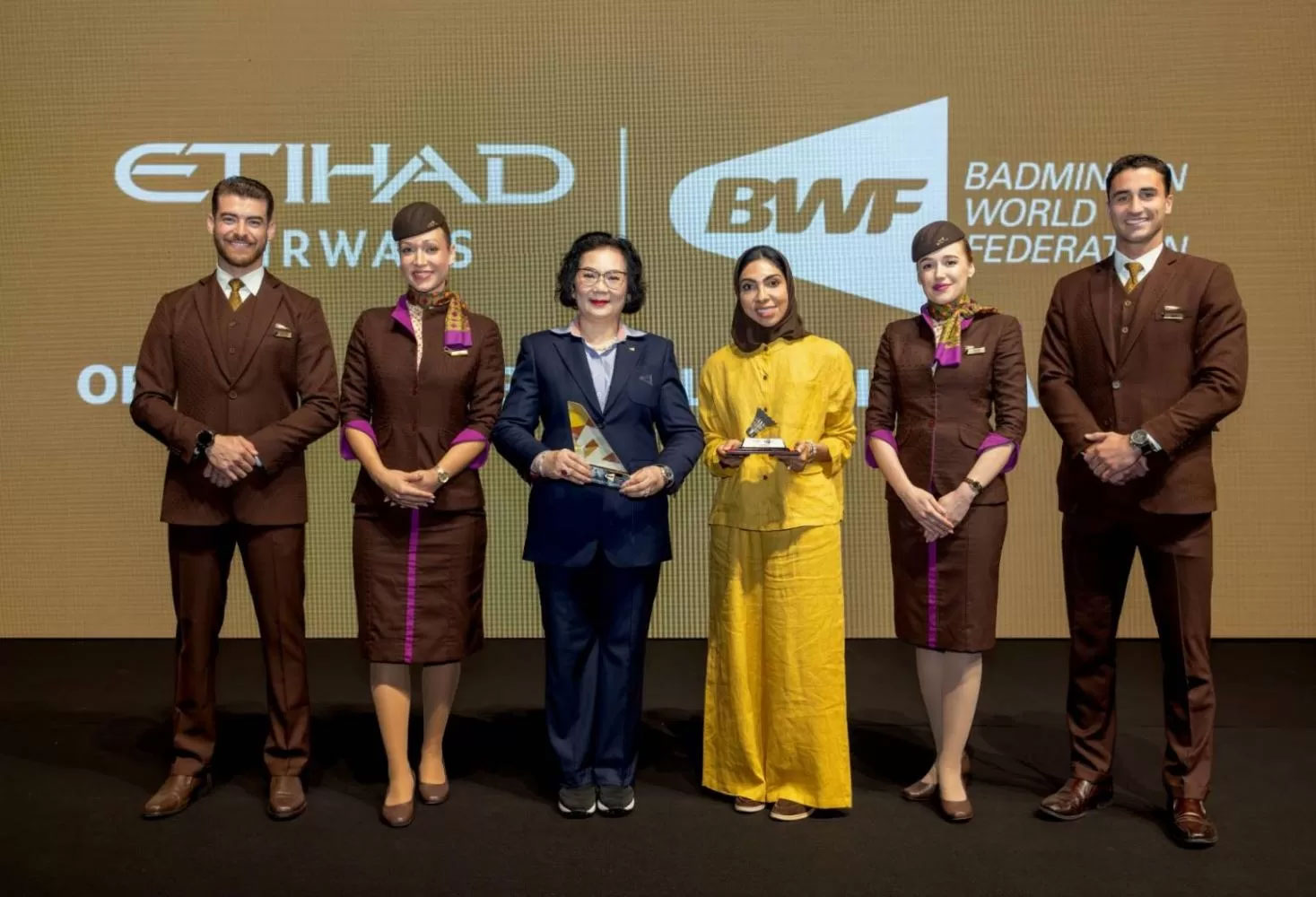 Khunying Patama และ Dr Nadia Bastaki หัวหน้าประชาชนและเจ้าหน้าที่กิจการองค์กรของ Etihad เข้าร่วมทีมงาน Etihad Cabin ในระหว่างการเปิดเผยการเป็นหุ้นส่วนที่ Petronas Malaysia Open 2025 ที่ Axiata Arena ผู้นำทั้งสองกับดร. บาสกิกิเป็นสีเหลืองเป็นประธานในการประกาศ
