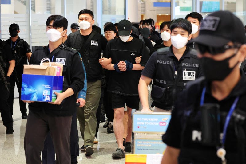 Police officers escort South Korean deportees suspected of being involved in online scam operations in Cambodia upon their arrival at the Incheon International Airport in Incheon, South Korea, on Saturday. (Reuters photo)