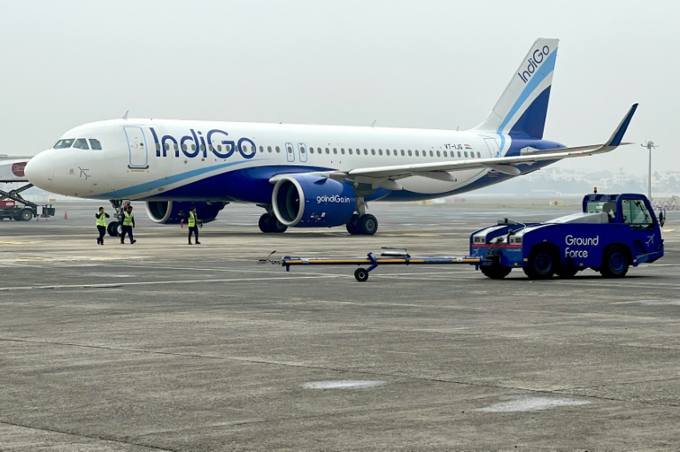 Ground staff walk past an IndiGo airlines aircraft taxiing in the apron at the Netaji Subhash Chandra Bose International Airport in Kolkata in February 2024. (Photo: AFP)